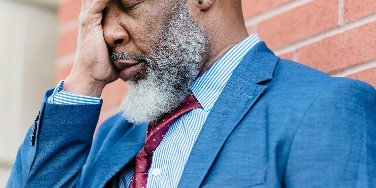 A man looking contemplative, perhaps holding back emotions, illustrating the societal pressure on men to hide vulnerability.