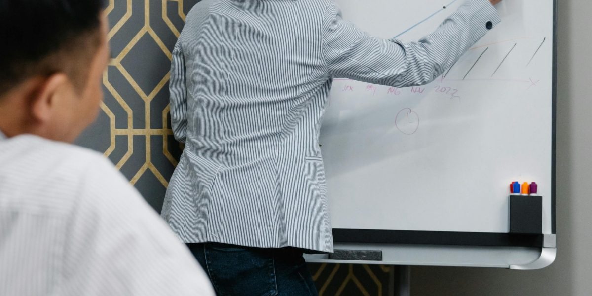 A person actively outlining goals on a whiteboard or notebook, representing the forward-focused approach of life coaching.