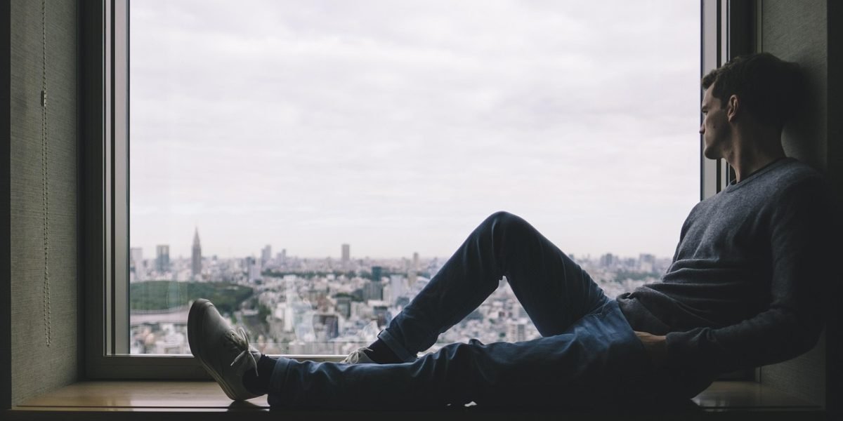 A man alone in a public setting, visually representing feelings of isolation and disconnection.