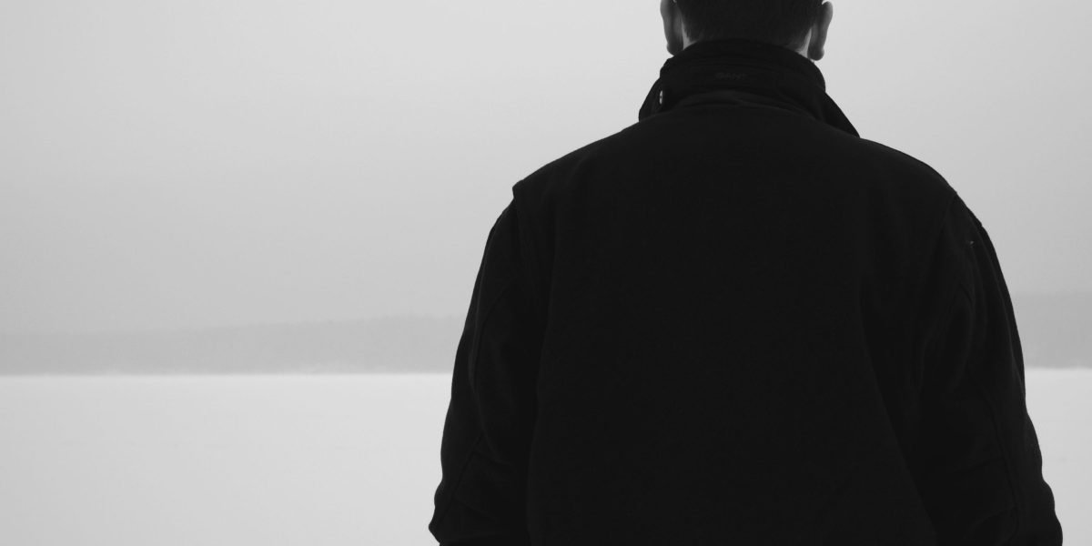 A man sitting alone, looking withdrawn or isolated, illustrating how mental health challenges can manifest.