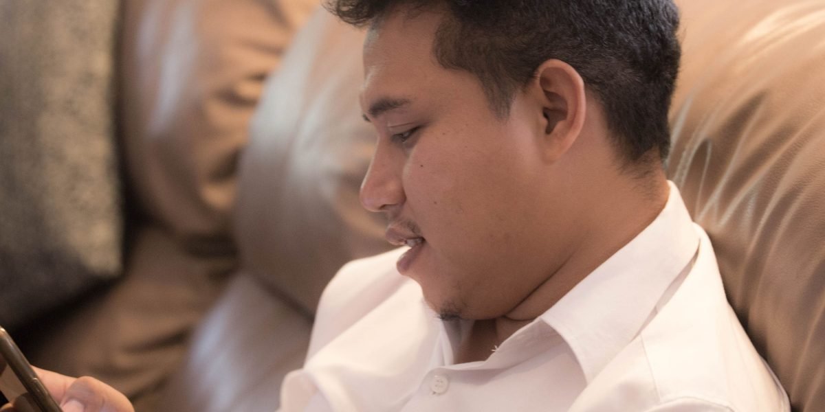 A man comfortably using a mental health app on a mobile device from his home, highlighting accessibility of digital CBT.