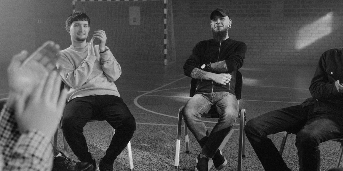 A group of men in a relaxed setting, actively listening and contributing to a supportive discussion.