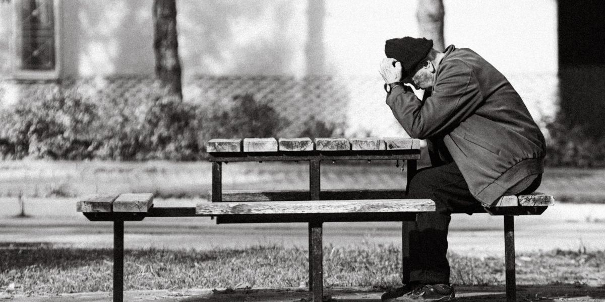 A man sitting alone, appearing self-reliant and deep in thought, perhaps grappling with internal emotions.
