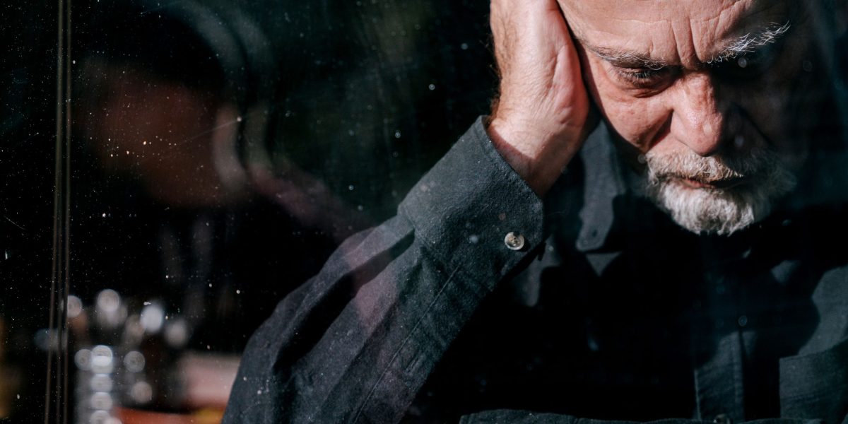 A man appearing overwhelmed, symbolizing the mental spiral that can accompany chronic loneliness.