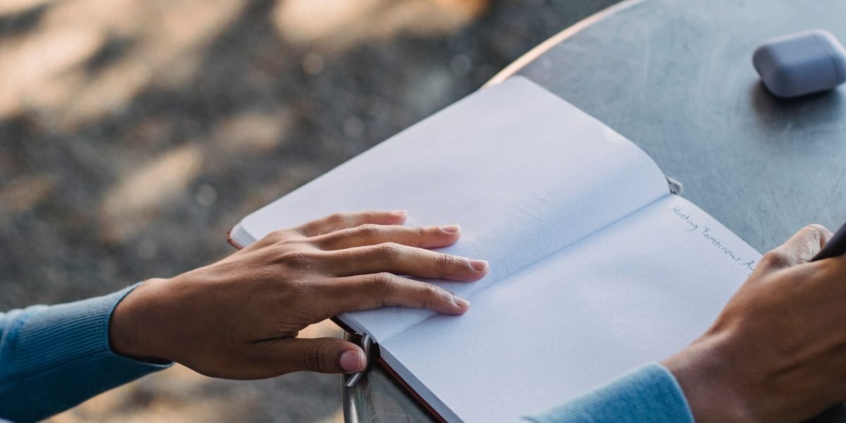 A person diligently writing notes, representing the act of tracking behavioral logs and mood for therapy.