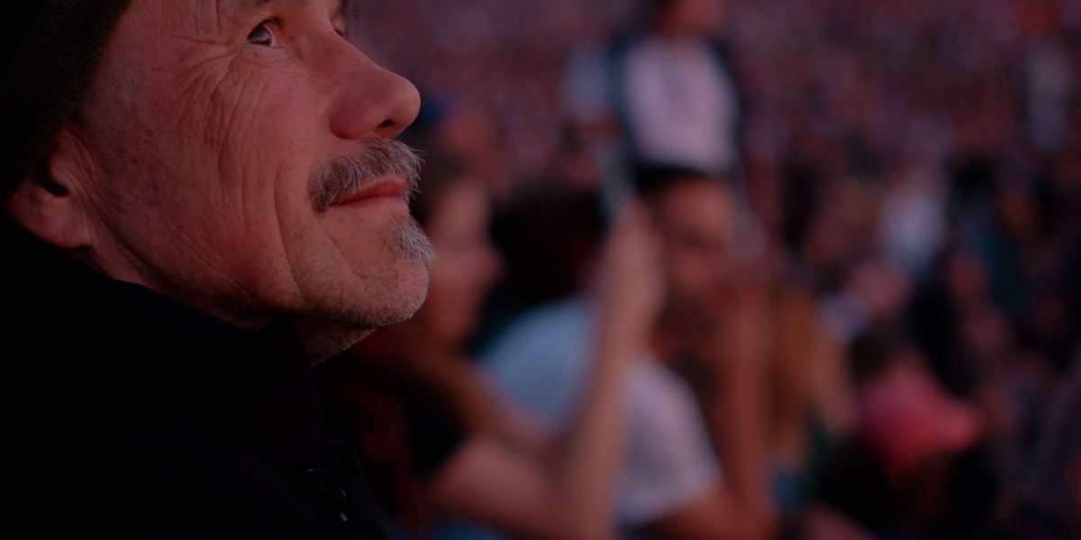 A man stands in a bustling crowd, yet a palpable sense of isolation surrounds him, reflecting the quiet ache of disconnection discussed in the male loneliness epidemic.