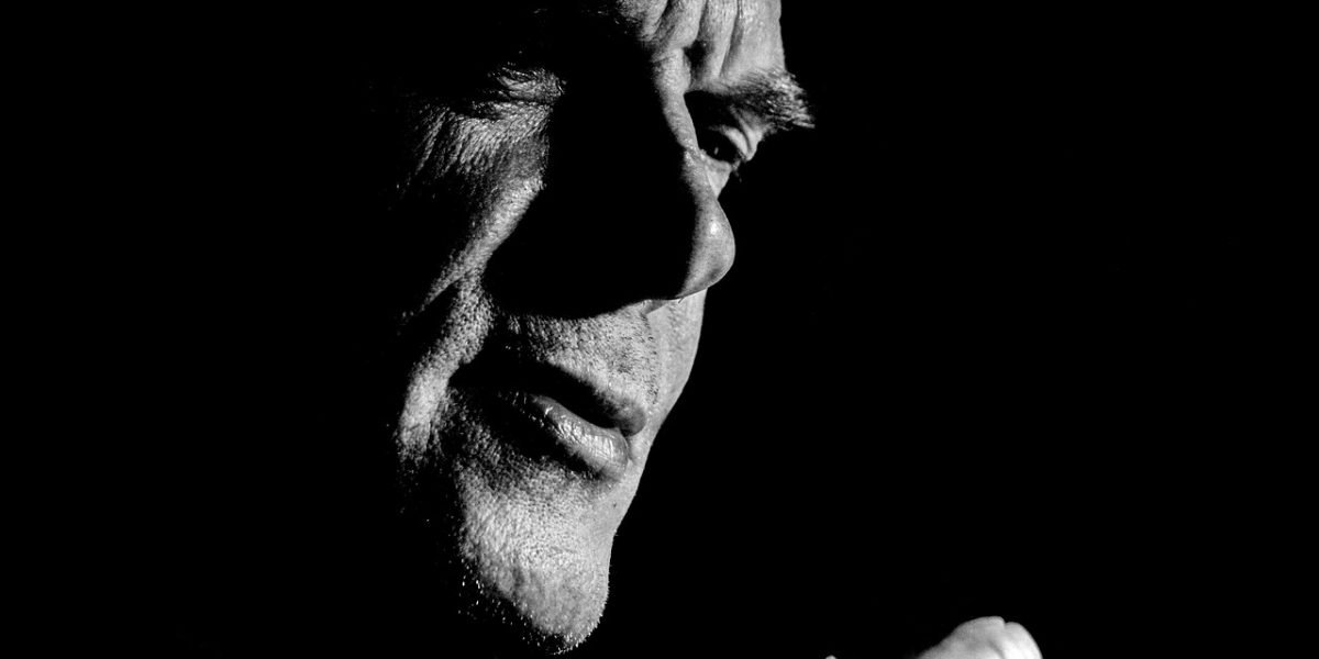 A man gazes thoughtfully, contemplating the societal messages like 'man up' that often discourage emotional expression and contribute to male isolation.