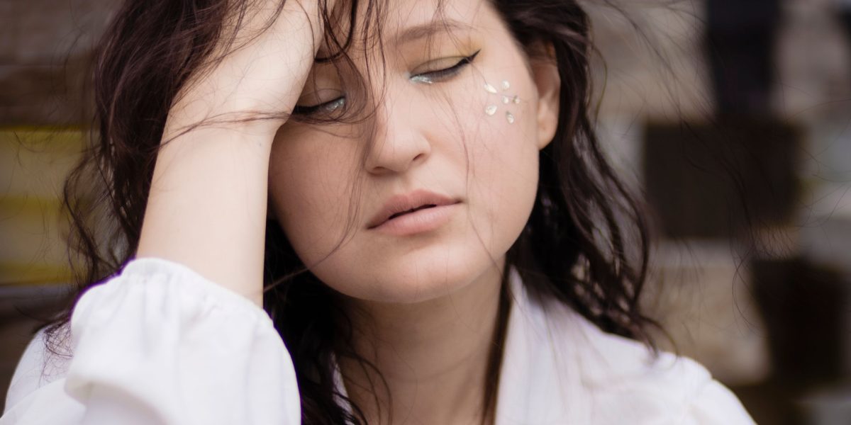 A person sits contemplatively, reflecting on difficult emotional situations and feeling a sense of entrapment.