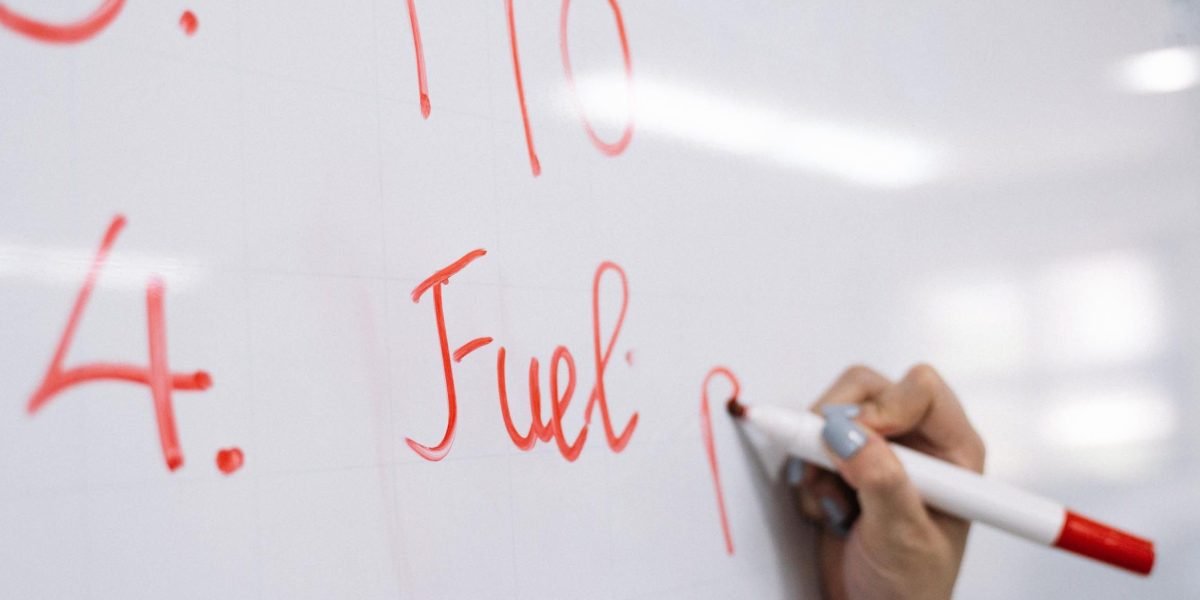 A person actively engaged in identifying and articulating complex patterns or steps on a whiteboard, symbolizing clarity and strategy.